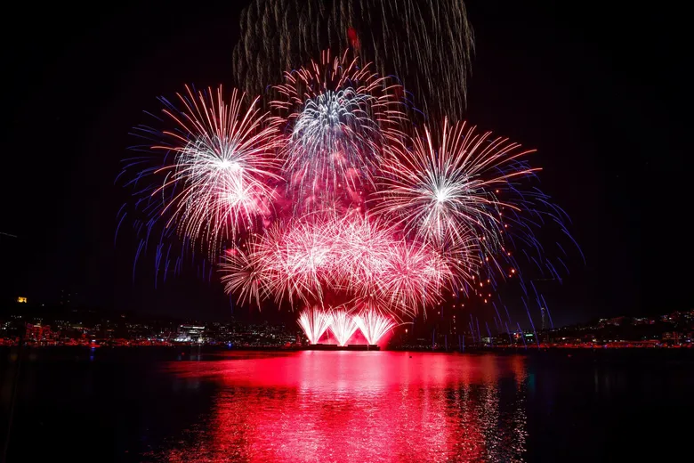 Fireworks bursting over Lake Union in Seattle on July 4th, with colorful reflections on the water